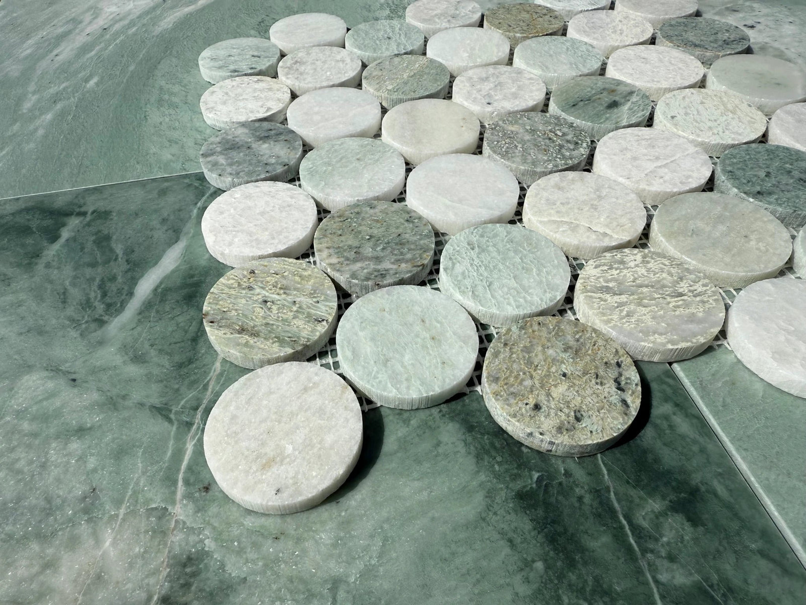 Tilehouz Ming Green Marble Large 2-inch Penny Mosaic with dozens of green and white marble penny discs on mesh backing.