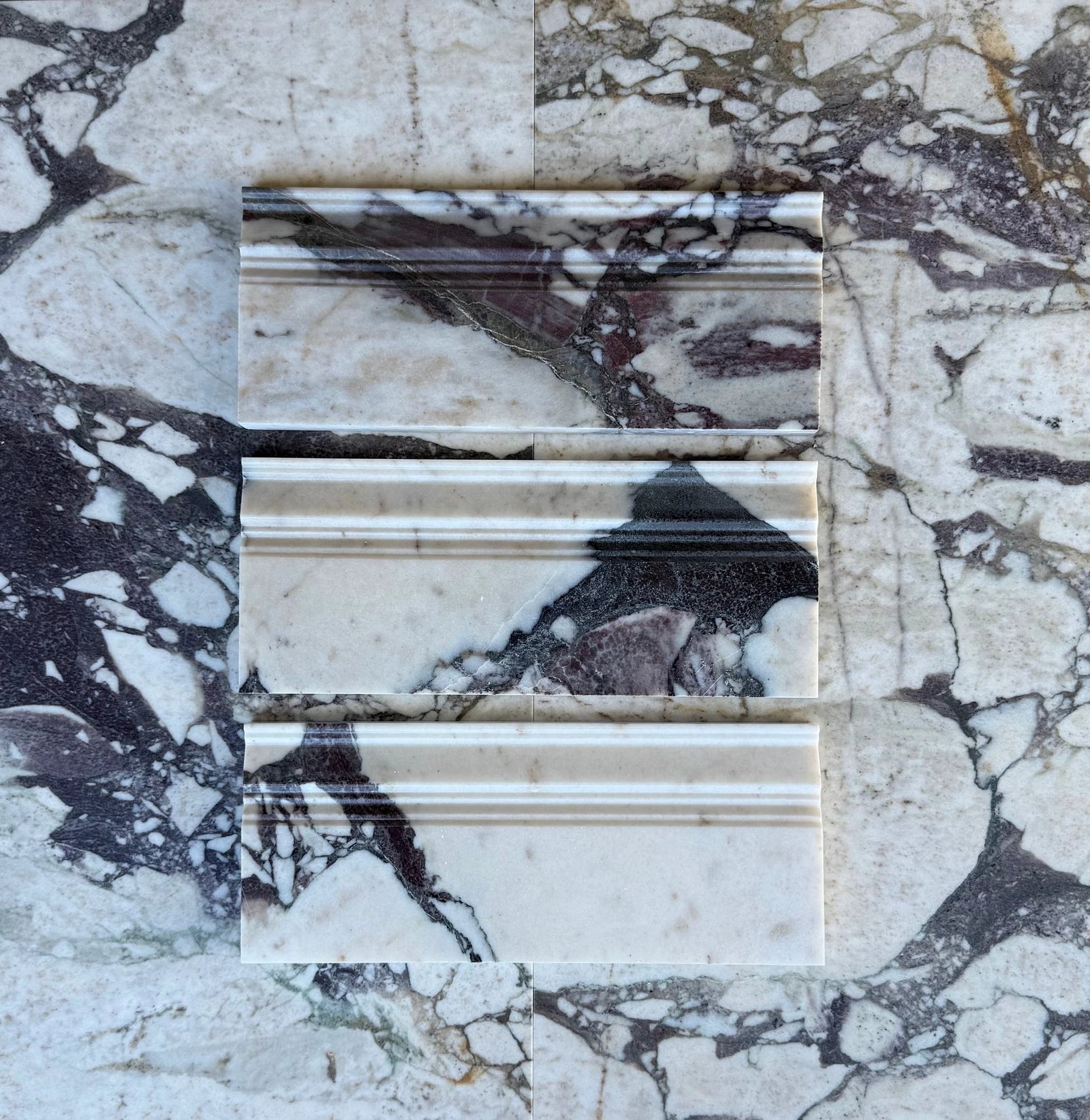 Tilehouz Calacatta Viola marble baseboard samples in three pieces with white background and purple veining.