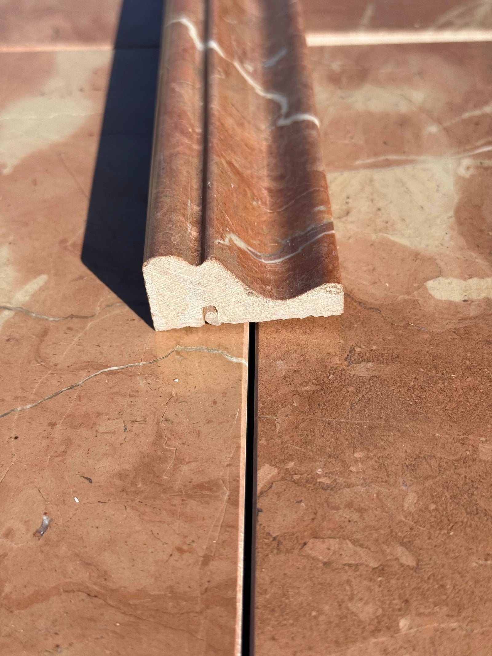 Rojo Alicante marble crown chair rail in red-brown with white veining