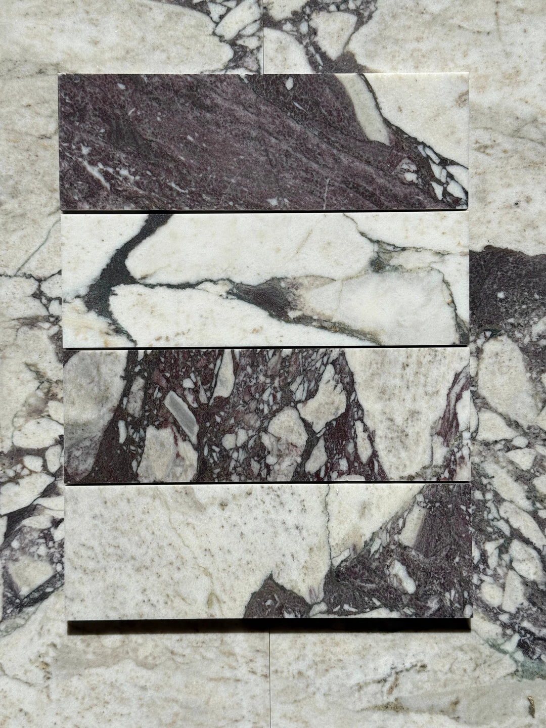 Calacatta Viola marble tile 4x12 by Tilehouz; five stacked samples in white with purple veining.