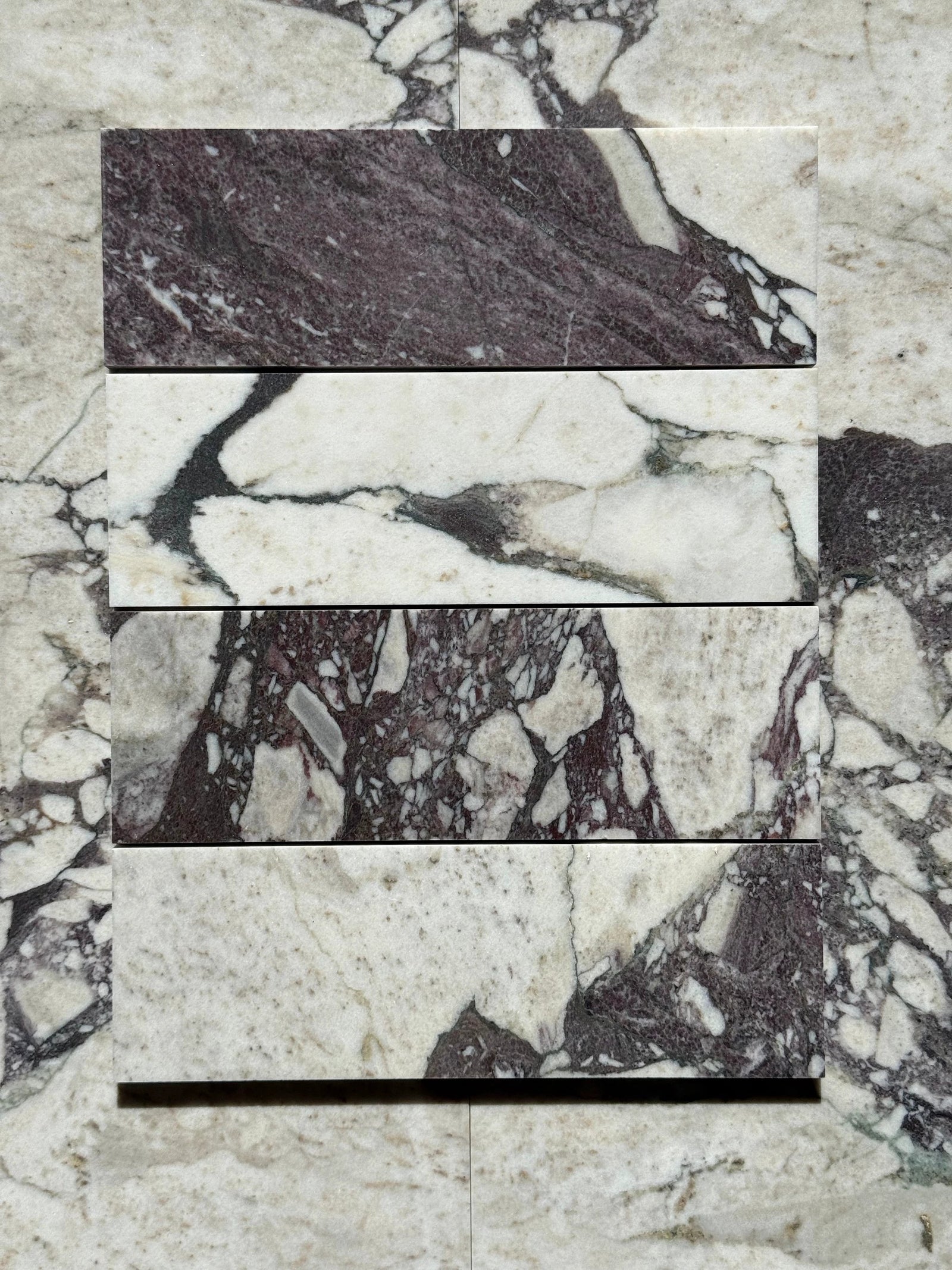 Calacatta Viola marble tile 4x12 by Tilehouz; five stacked samples in white with purple veining.