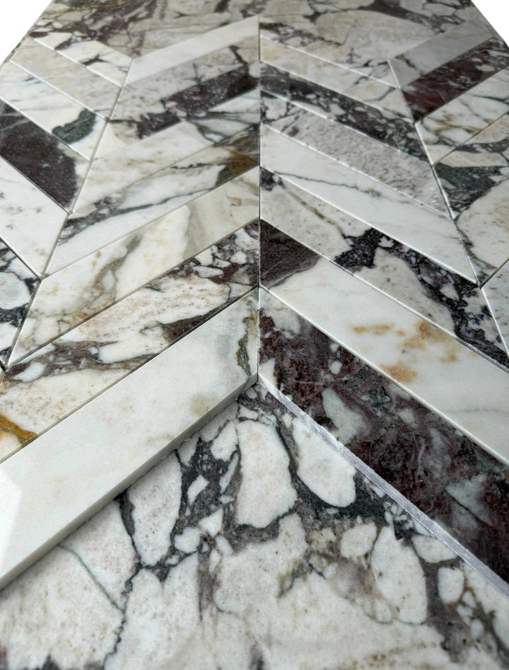 Tilehouz Calacatta Viola marble 2x8 chevron mosaic wall tile in white with gray and purple veining.