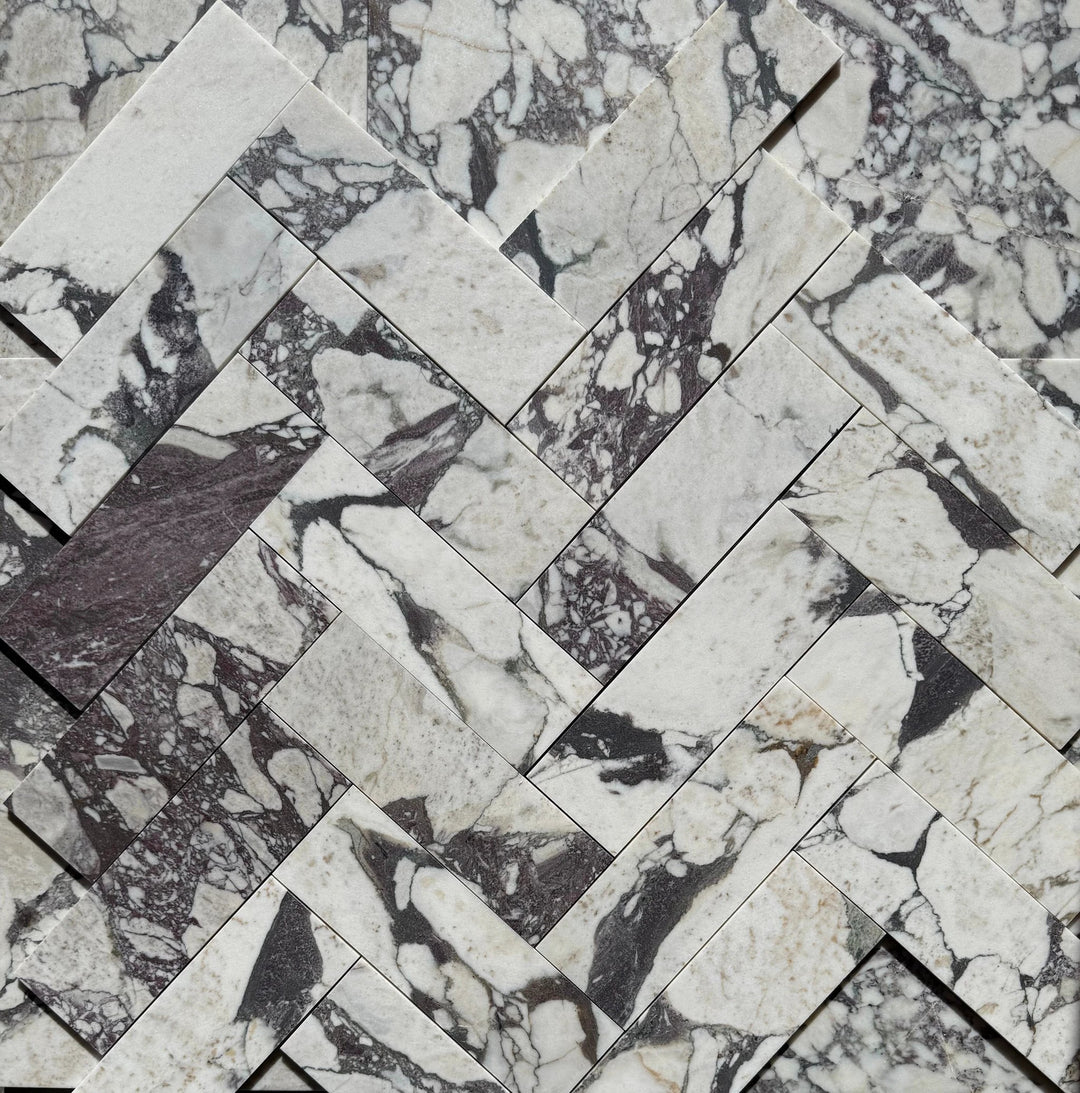 Calacatta Viola Marble Tile 4x12; white marble with dark gray veining arranged in a herringbone pattern.