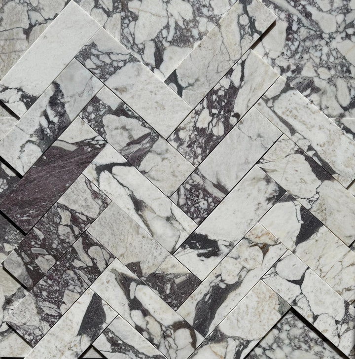 Calacatta Viola Marble Tile 4x12; white marble with dark gray veining arranged in a herringbone pattern.
