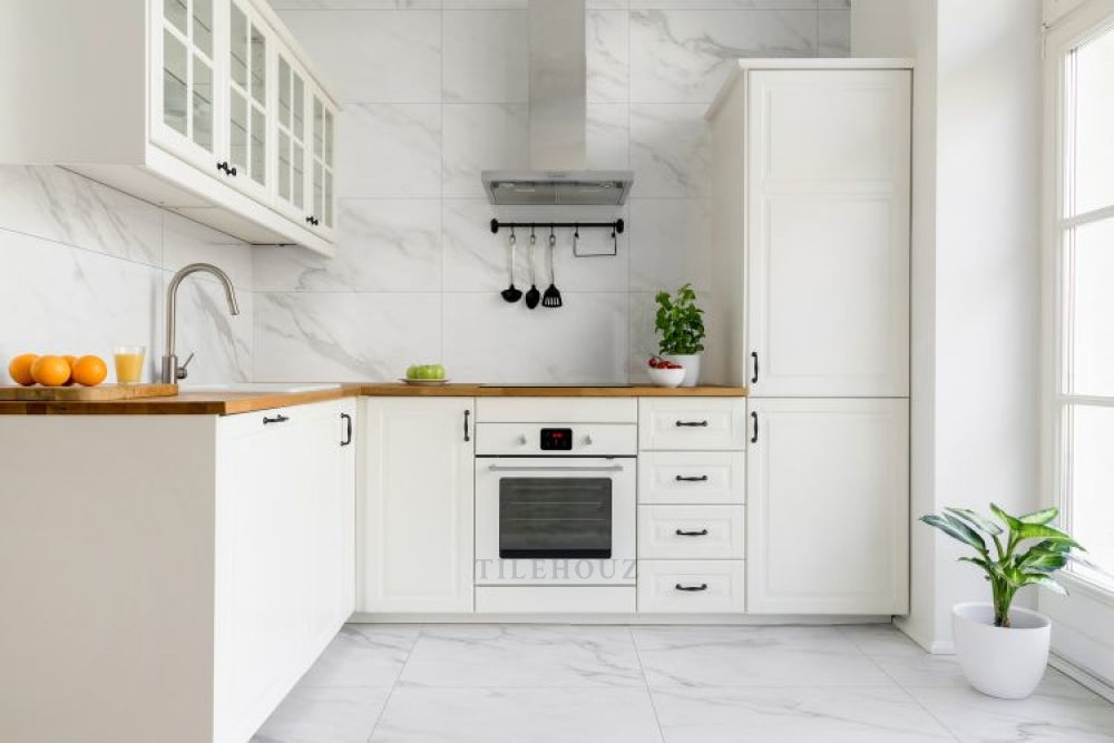Carenza Bianca polished porcelain tile 24 x 48 by Tilehouz for walls, shown in a white kitchen with marble backsplash