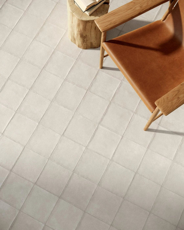 Terracreta Intarsio Argilla porcelain tile by Tilehouz; light gray floor tiles in a grid with wooden chairs.
